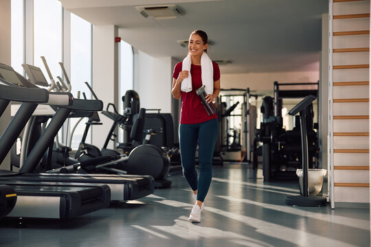 Young happy sportswoman walking through gym.