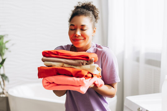 Housewife smelling fresh clean laundry in bathroom