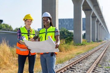 young multiracial female railway engineer,caucasian and african,inspecting at railroad tracks,concept of rail transport,train,railway infrastructure standard inspection work and maintenance