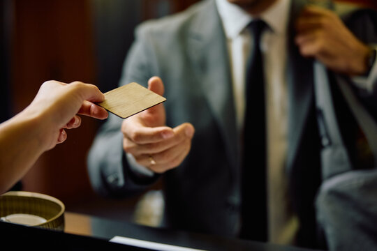 Close up of businessman receiving membership card at gym's reception desk.
