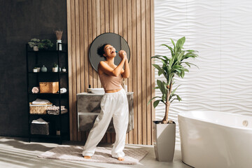 Young woman singing with toothbrush in modern bathroom