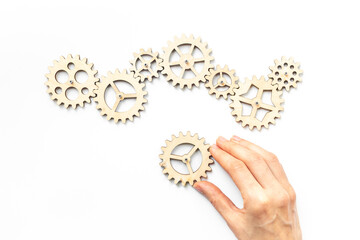 Hand is adding a cog wheel to a chain of gears. Idea or solution concept
