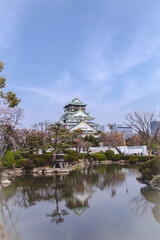 Osaka Castle, A beautiful park with a pond and a large building in the background