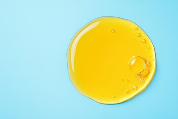 Round yellow oil sample on light blue background cosmetic serum with hyaluronic acid retinol and collagen