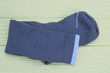 one gray long fabric sock lies on a yellow wooden table