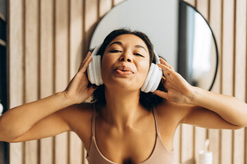 Young woman enjoying music with wireless headphones in bathroom