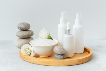 Tray on bathroom table with skin care cosmetics and white roses