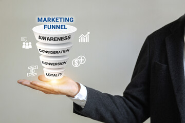 A businessman holds a pyramid with the word marketing funnel on it. The pyramid has 4 levels, each...