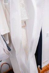 Close-Up Detail of Hanging White Clothing with Delicate Textures and Pearl Accessories
