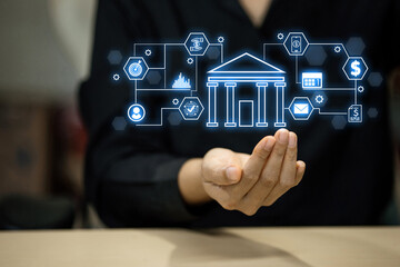 A hand holding a screen with a bank logo and other icons. The hand is holding the screen in a way that it looks like a bank