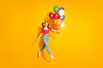 Photo portrait of young red hair funky positive girl wearing blouse and jeans holding air balloons isolated on yellow color background