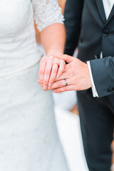 Obraz premium Bride and Groom Holding Hands with Wedding Rings in Focus