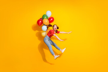 Photo portrait of young red hair funky positive girl wearing stylish look but flying helium air balloons isolated on yellow color background