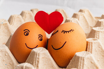 Painted eggs in a tray with a paper heart above them, love concept