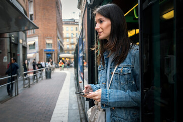 Beautiful woman using her smartphone while waiting for the tram at the station
