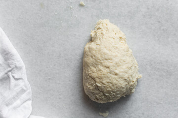 Overhead view of challah dough being kneaded on a white countertop, top view of homemade challah dough being mixed on white granite countertop, process of making challah