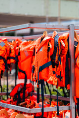 Multiple Bright Orange Life Jackets Arranged on a Rack for Safety Equipment Display