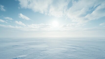 Fototapeta premium A brilliant sun casts its warm light over an expansive, icy terrain, where fluffy clouds drift lazily beneath a pristine blue sky