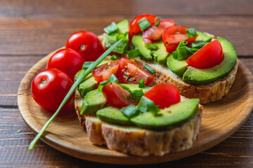 Avocado toast topped with tomato and green onion on a slice of carrot bread