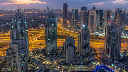 Fototapeta premium Dubai Marina skyscrapers and jumeirah lake towers view from the top aerial night to day timelapse in the United Arab Emirates.