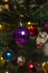 purple Christmas decorations on a christmas tree, sparkly purple christmas tree baubles on artificial tree, closeup view of purple christmas tree ornaments