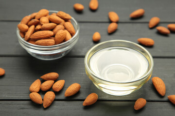 Fresh almond oil with almond nuts on black wooden background.