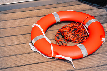 Bright Orange Lifebuoy with Rope on Wooden Dock Surface in Sunlight