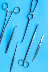 Surgical scissors and forceps. Medical metal hand tools and equipment on blue, top view