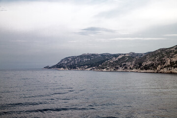 Coastal view showcasing rocky cliffs and calm waters on a cloudy day near a serene shoreline with gentle waves