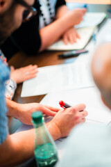 Close-Up of a Group Meeting with Hands Writing on Papers at a Desk