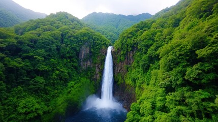 Fototapeta premium Majestic waterfall cascading through lush green mountains.
