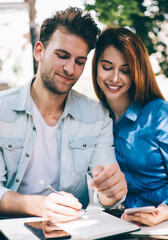 Smiling couple with notepad at table cafeteria