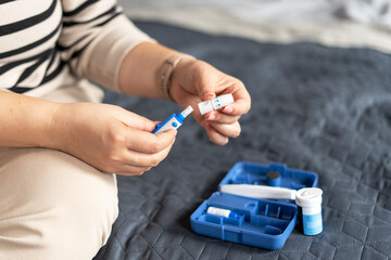 Close up of female hands taking lancet on finger for checking blood sugar level