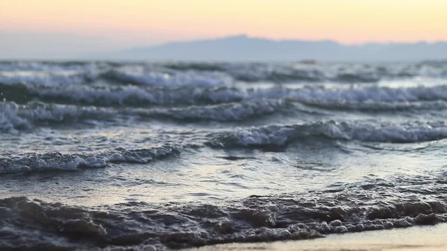 Sunset on the sea, waves on the beach. Beautiful landscape on the Bolerian Sea. View of the sea with small waves. View of the waves on the sea from a lower angle. Salou, Spain