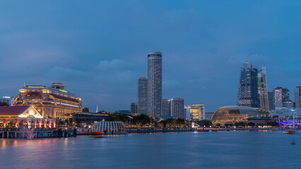 Fototapeta premium City skyline with skyscrapers and Esplanade Theatres on the Bay in Singapore at dusk, with beautiful reflection in water day to night timelapse