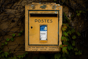 Old french La Poste mail box on the wall of the post office of the village.