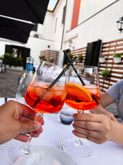 Two friends enjoying aperol spritz on a sunny outdoor patio. Venice, Italy.