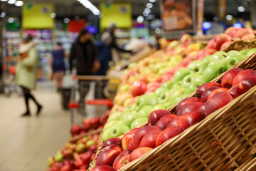 Red and green apples in a wicker baskets. Fresh harvest, ripe fruits in a supermarket