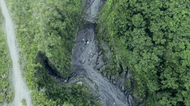 Aerial View of Dramatic Sand Mining Activity in Volcanic Lava Gorge Amid Foggy and Overcast Skies