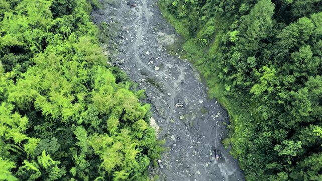 Aerial View of Dramatic Sand Mining Activity in Volcanic Lava Gorge Amid Foggy and Overcast Skies