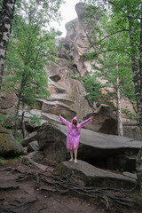 A woman wearing a pink raincoat in rocky forest. National park in the Krasnoyarsk region