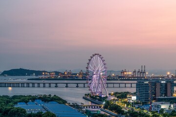 Vibrant summer sunset over Happy Harbor in Qianhai Bay, Shenzhen showcasing the iconic Ferris wheel and waterfront activity