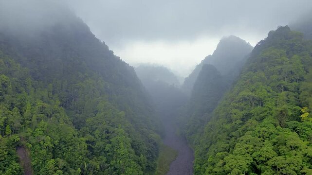 Dramatic Aerial Scene of Towering Mountain Peaks, Dense Rainy Forests  and Volcanic Lava Canyon in Foggy Weather