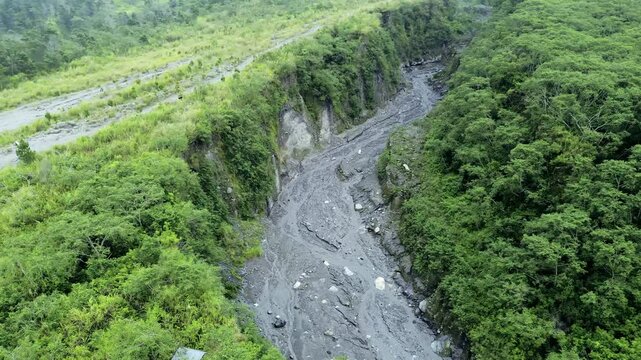 Aerial View of Dramatic Sand Mining Activity in Volcanic Lava Gorge Amid Foggy and Overcast Skies