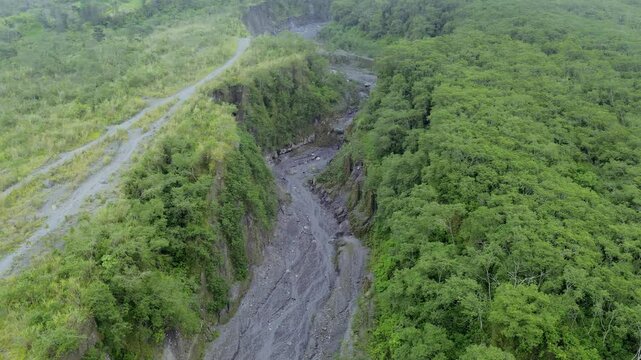 Aerial View of Dramatic Sand Mining Activity in Volcanic Lava Gorge Amid Foggy and Overcast Skies