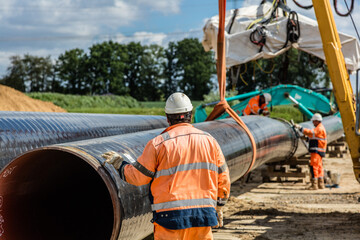 Kran hebt Rohr auf Baustelle zum Einschweißen