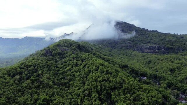 Aerial view of Misty Green limestone karst Mountains with Dense Forest and Rolling Clouds