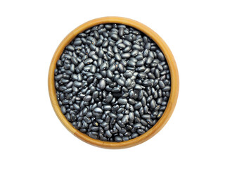 Closeup black beans in wooden bowl isolated on white background Top view. Flat lay.