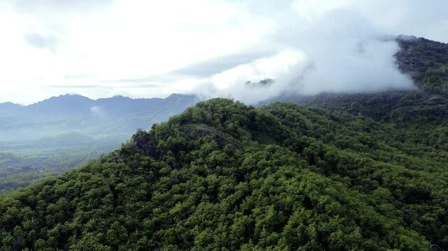 Aerial view of Misty Green limestone karst Mountains with Dense Forest and Rolling Clouds