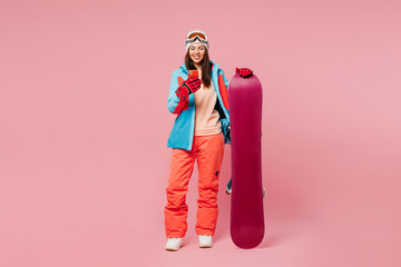 Full body young fun woman wear warm blue padded jacket ski goggles mask spend weekend winter season...